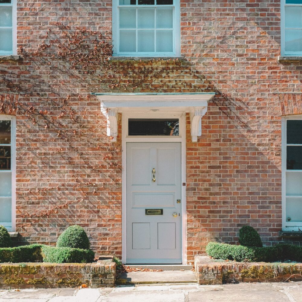 Front of a house with closed blue-tinted door by Viktor Forgacs on Unsplash